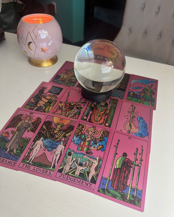A crystal ball sits on an array of pink tarot cards.