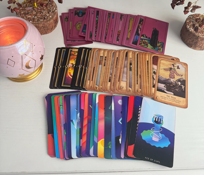 Four different decks of tarot cards spread out on a table to show the different designs.